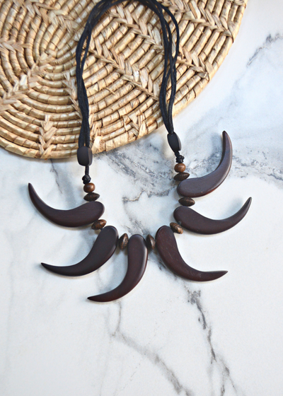 brown wooden tribal necklace with beads laid on a marble surface and woven matt