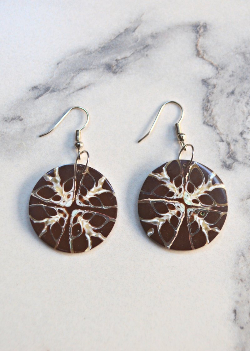 two Brown Shell Disc Earrings With Unique White Detail with ear wire laid on a marble surface
