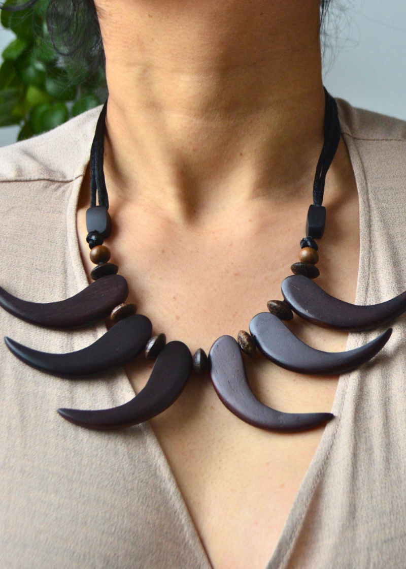brown wooden tribal necklace with beads sat across a woman&
