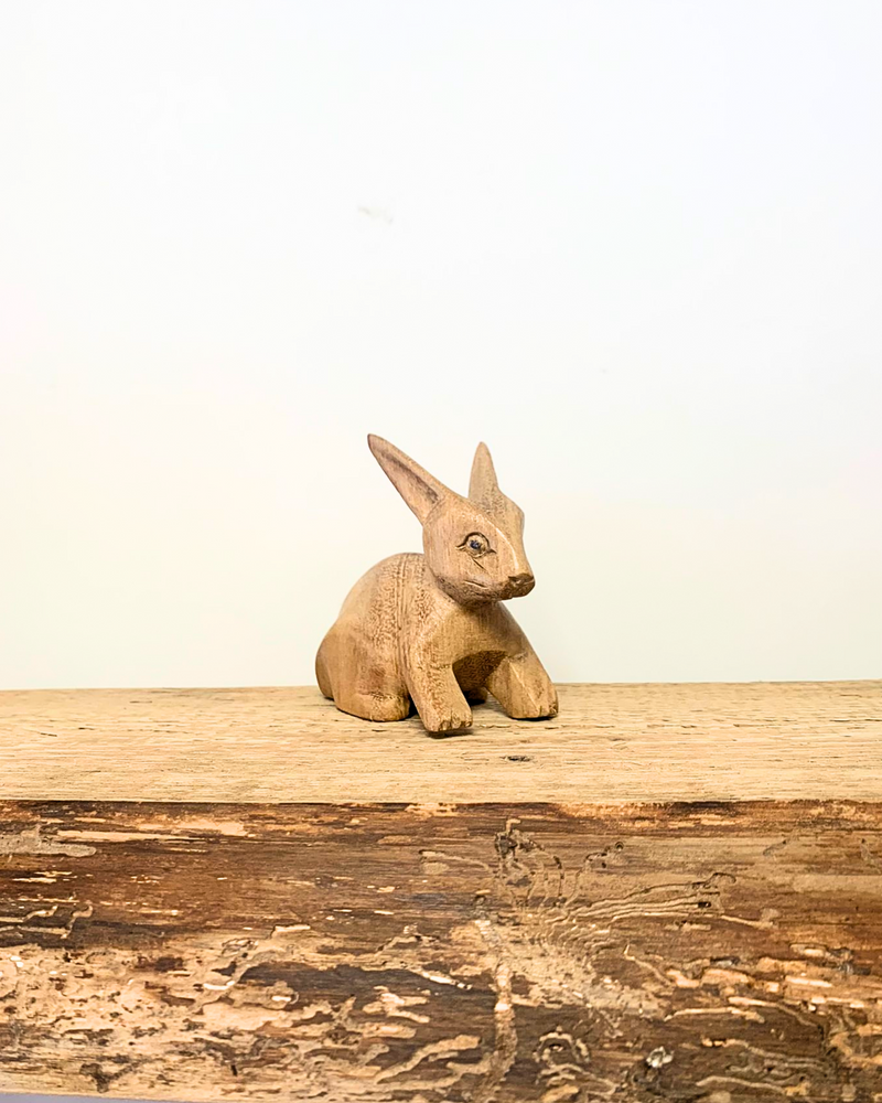 carved wooden rabbit ornament sat on a wooden surface