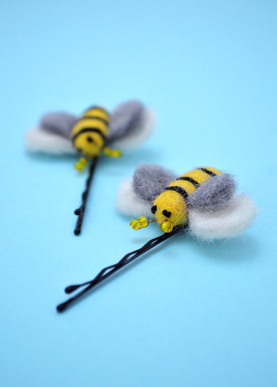 mini yellow felt bees with black stripes, yellow beads and grey and white wings attached to hair grips