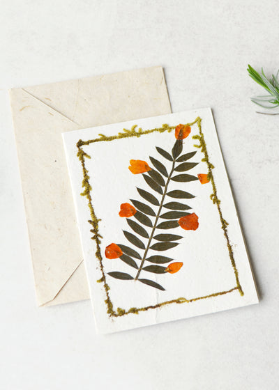 lokta paper greetings card with a dried flower on the front laid next to an envelope