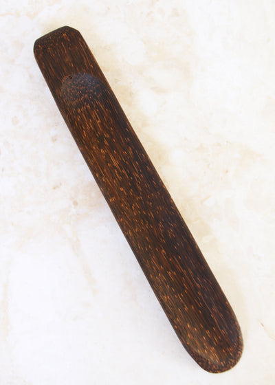 coconut palm wood incense holder laid on a marble surface