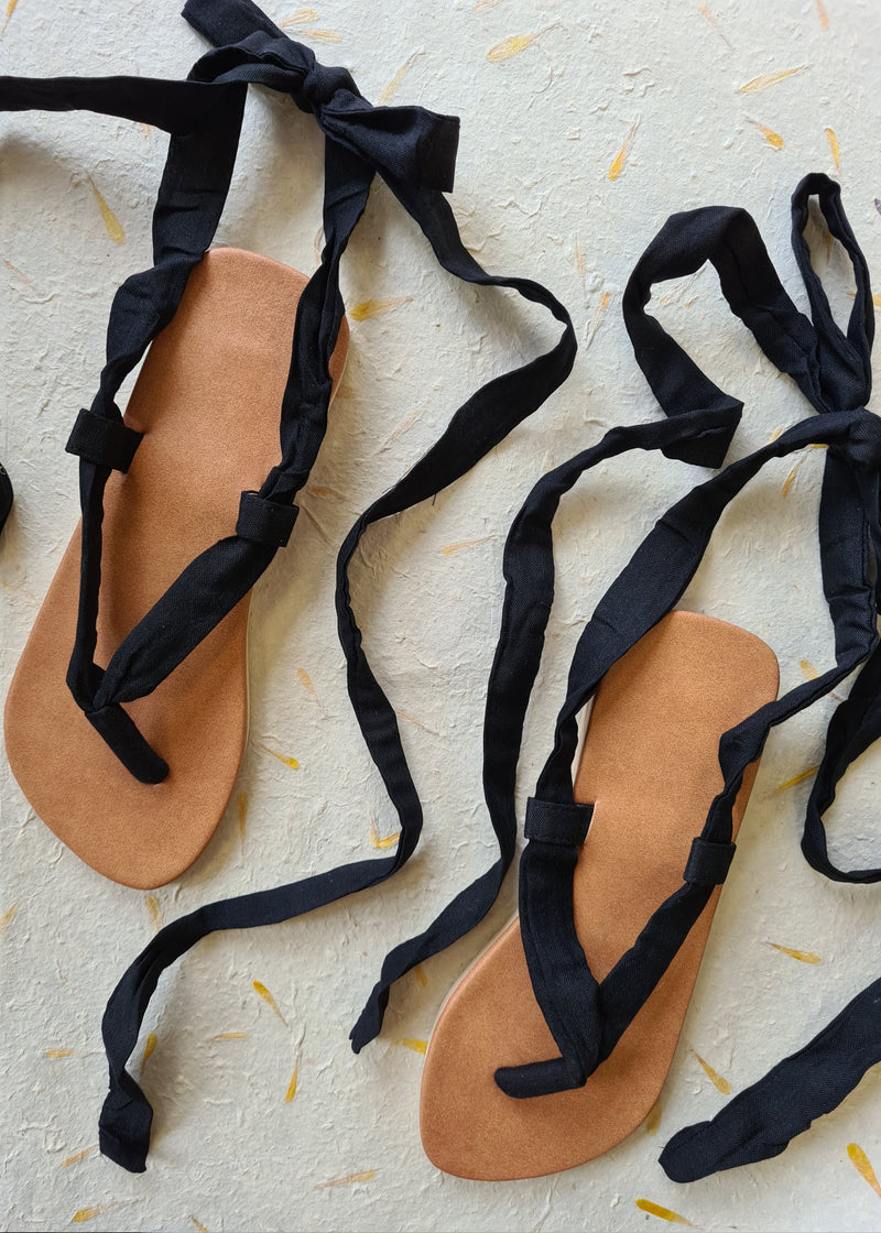two handmade black lace up sandals tied into loose bows
