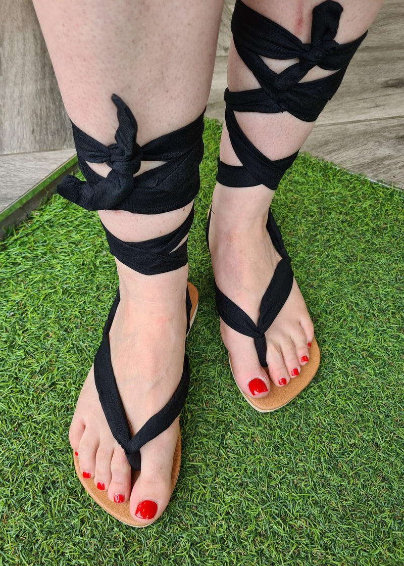 close up of woman wearing handmade black lace up sandals tied up in gladiator style