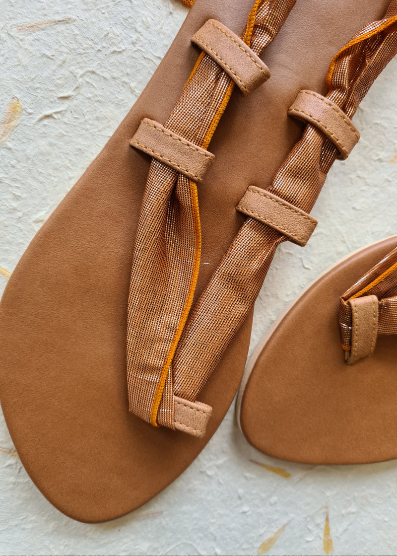 close up of a pair of brown metallic lace up sandals showing the straps and vegan leather sole and strap holders