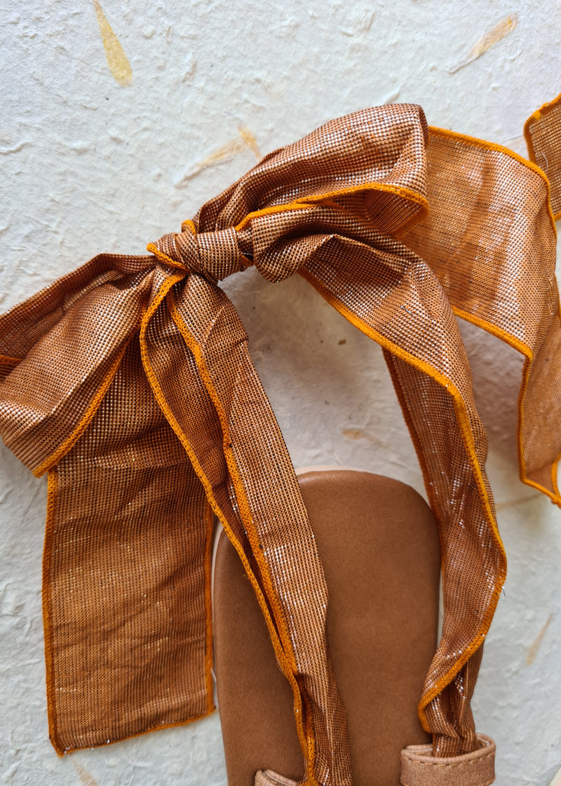 close up of the tied bow on brown metallic lace up sandal