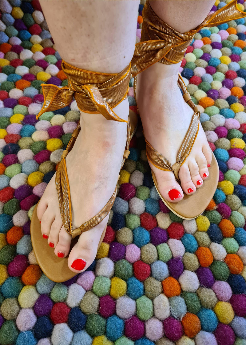 woman wearing pair of brown metallic lace up sandals tied in gladiator style with tie at the front