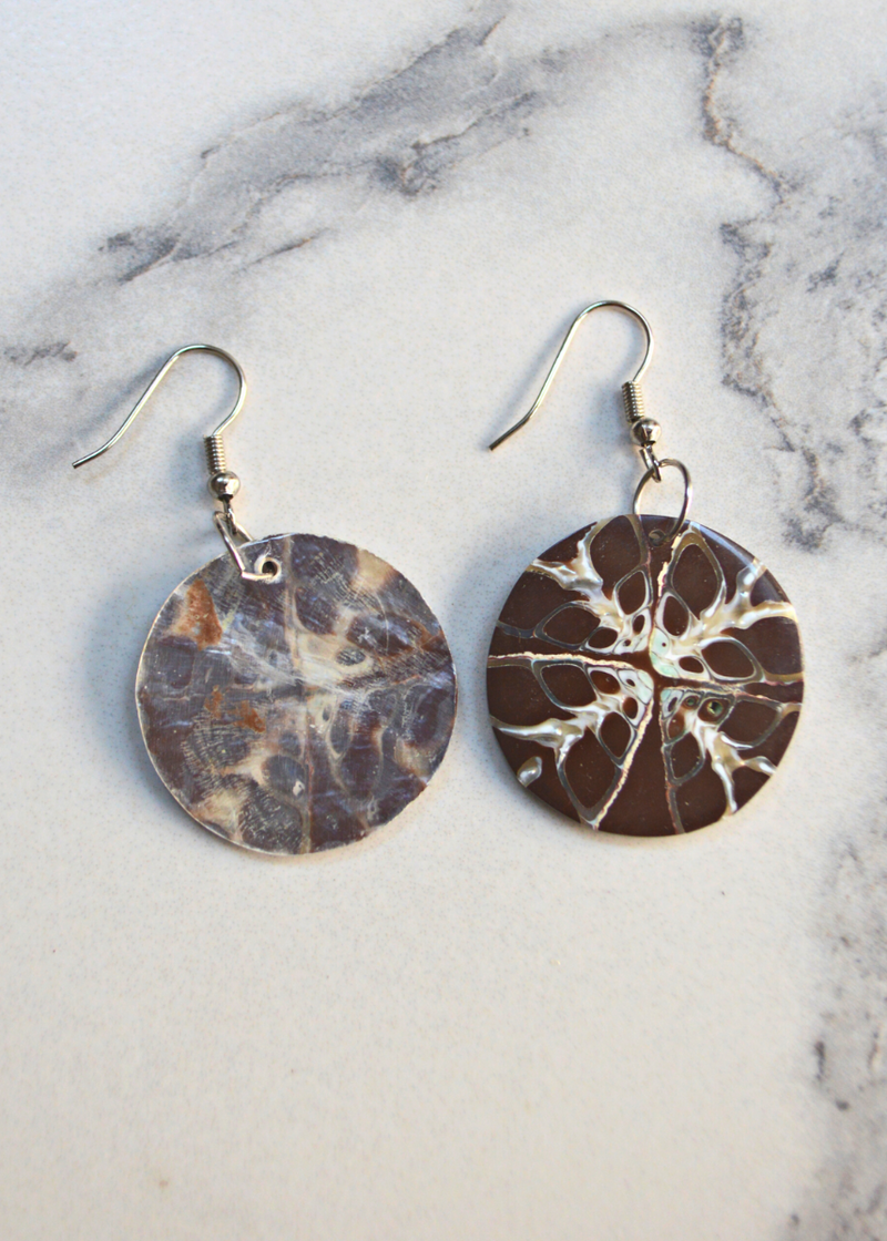 two Brown Shell Disc Earrings With Unique White Detail with ear wire laid on a marble surface, one showing the front and the other showing the backl