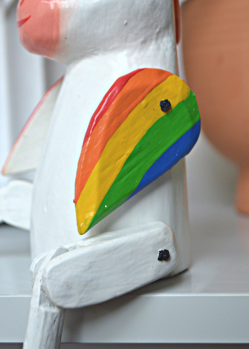 close up of wooden unicorn rainbow coloured wing sat on a white wooden shelf