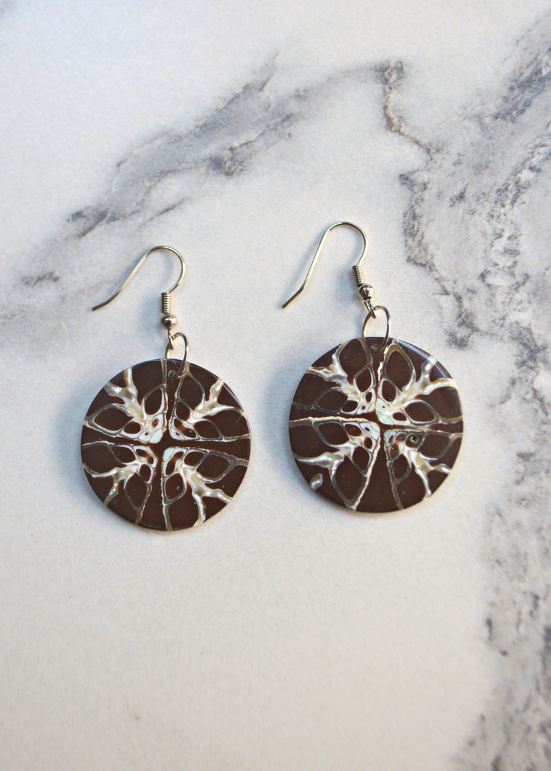 two Brown Shell Disc Earrings With Unique White Detail with ear wire laid on a marble surface