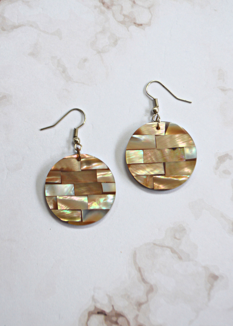 light brown Mother of Pearl Disc Earrings laid on a marble textured background