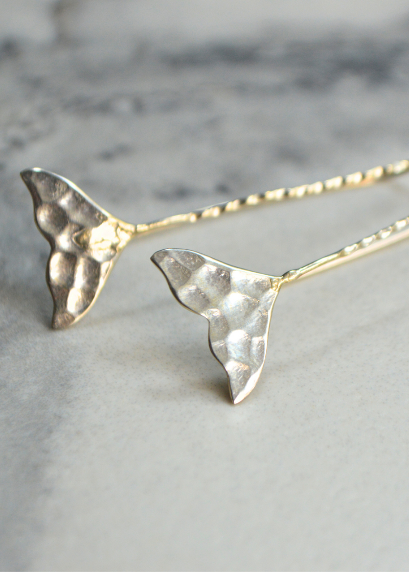 close up of 925 sterling silver whale tail earrings with long fish hook placed on a white marble background