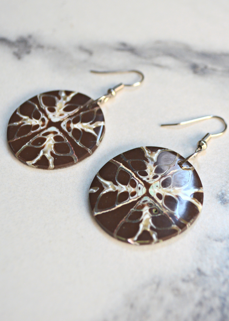 close up of two Brown Shell Disc Earrings With Unique White Detail with ear wire laid on a marble surface