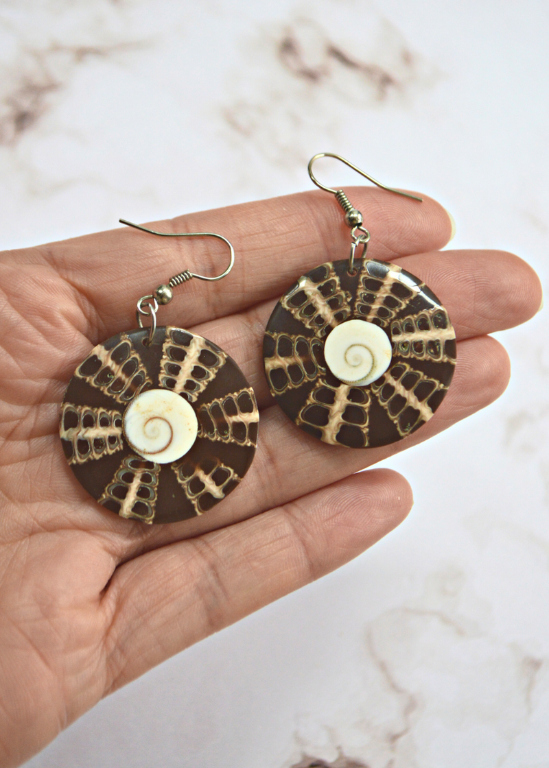 Dangle drop earrings with white shiva eye shell in the centre and brown pattern surrounding it laid in someone&