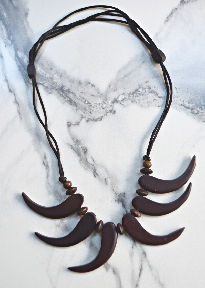brown wooden tribal necklace with beads laid on a marble surface