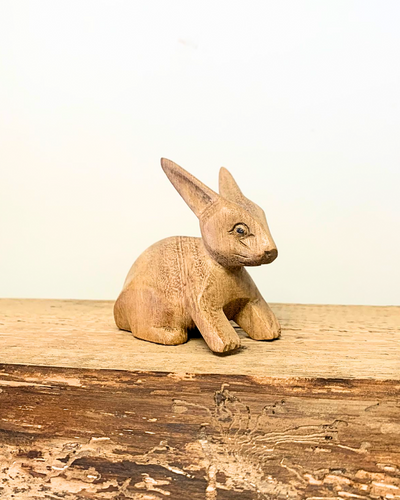 carved wooden rabbit ornament sat on a wooden surface