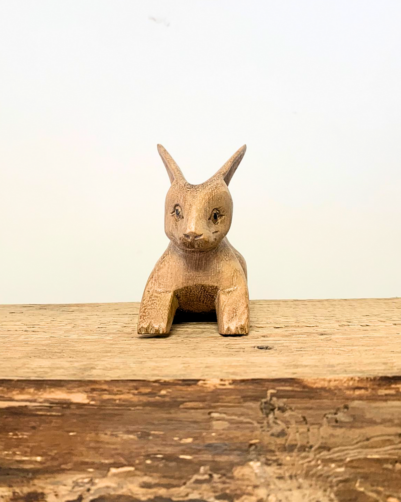 front view of carved wooden rabbit ornament sat on a wooden surface