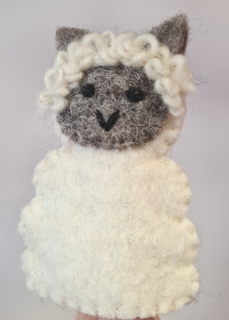 close up of a felt white sheep finger puppet with cute grey face and ears