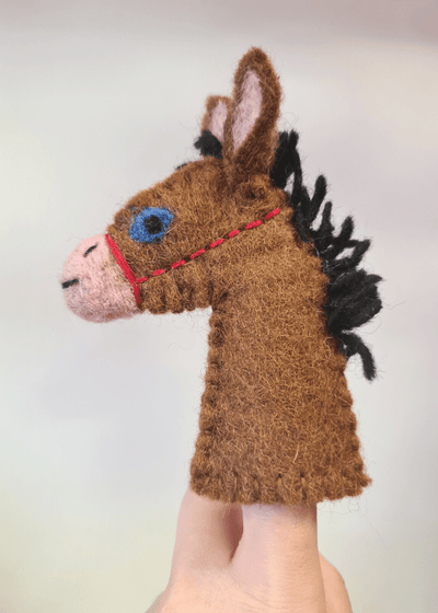 brown felt horse finger puppet with a black main, pink nose, blue eye and red bridle sat on a persons finger