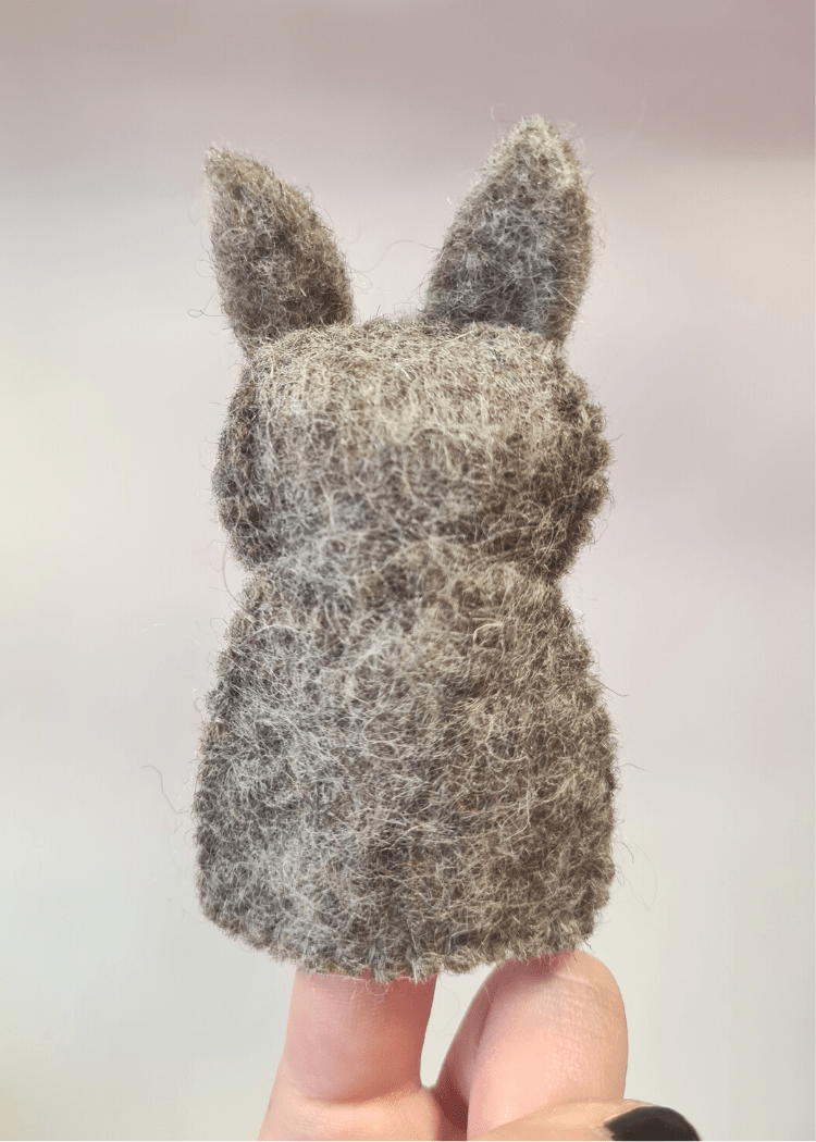 back of a felt grey wolf finger puppet sat on someone&
