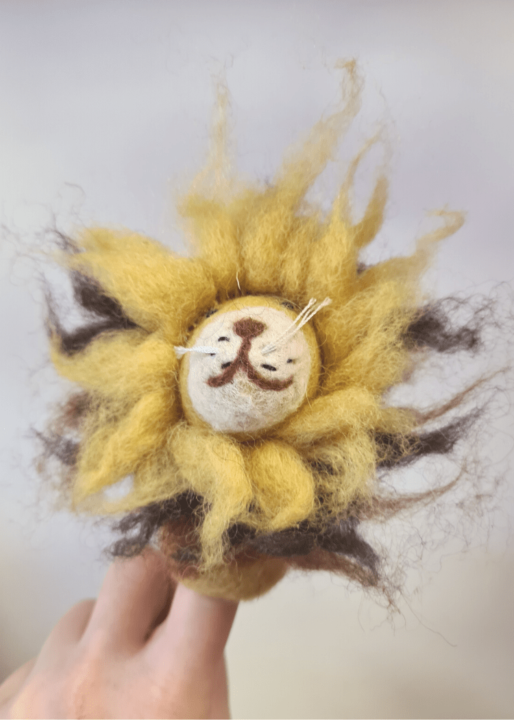 wild yellow felt lion with smiley brown face and fuzzy mane sat on someone&
