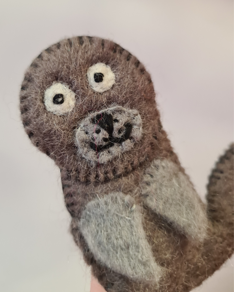 close up of a dark grey felt seal finger puppet with a sewn on smiley face