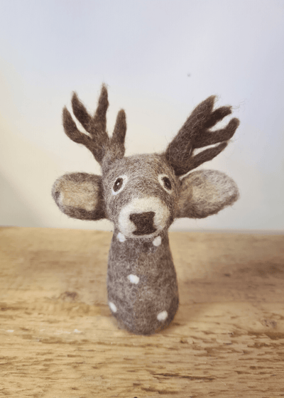 grey felt deer finger puppet with white spots, brown antlers and nose, a cute face and big ears sat on a wooden surface