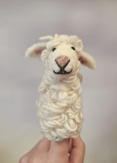 white felt sheep finger puppet with pink nose and black thread smile and eyes sat on someone's finger