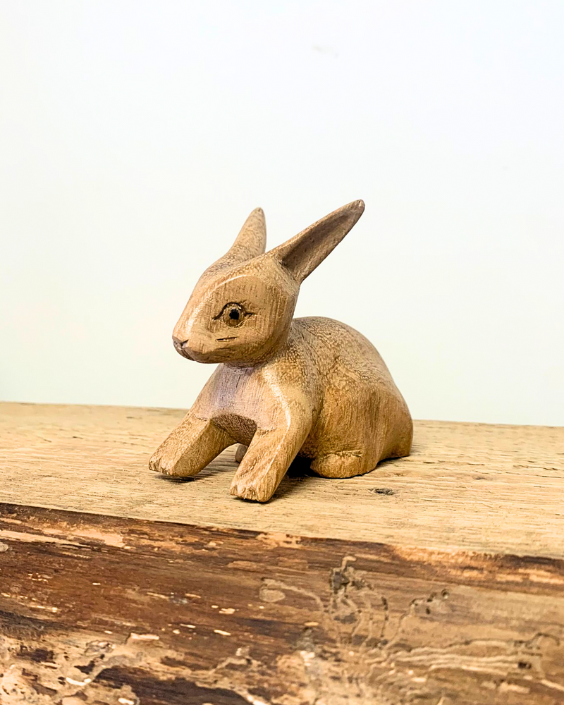 carved wooden rabbit ornament sat on a wooden surface