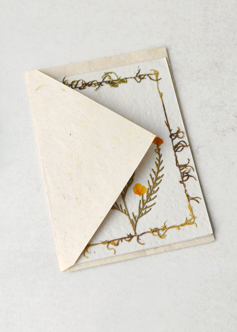 lokta paper greetings card with a dried flower on the front laid in an envelope
