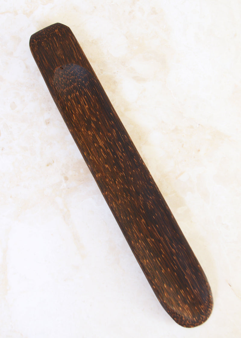 coconut palm wood incense holder laid on a marble surface