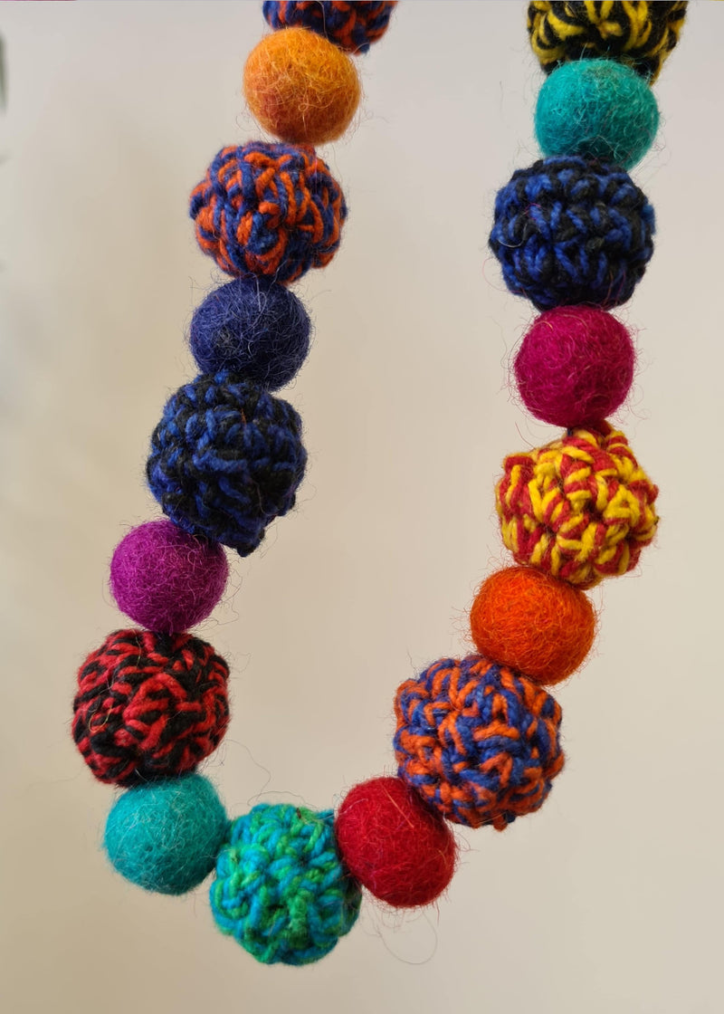 close up of hanging Large Felt Multi Colour Pom Pom Necklace