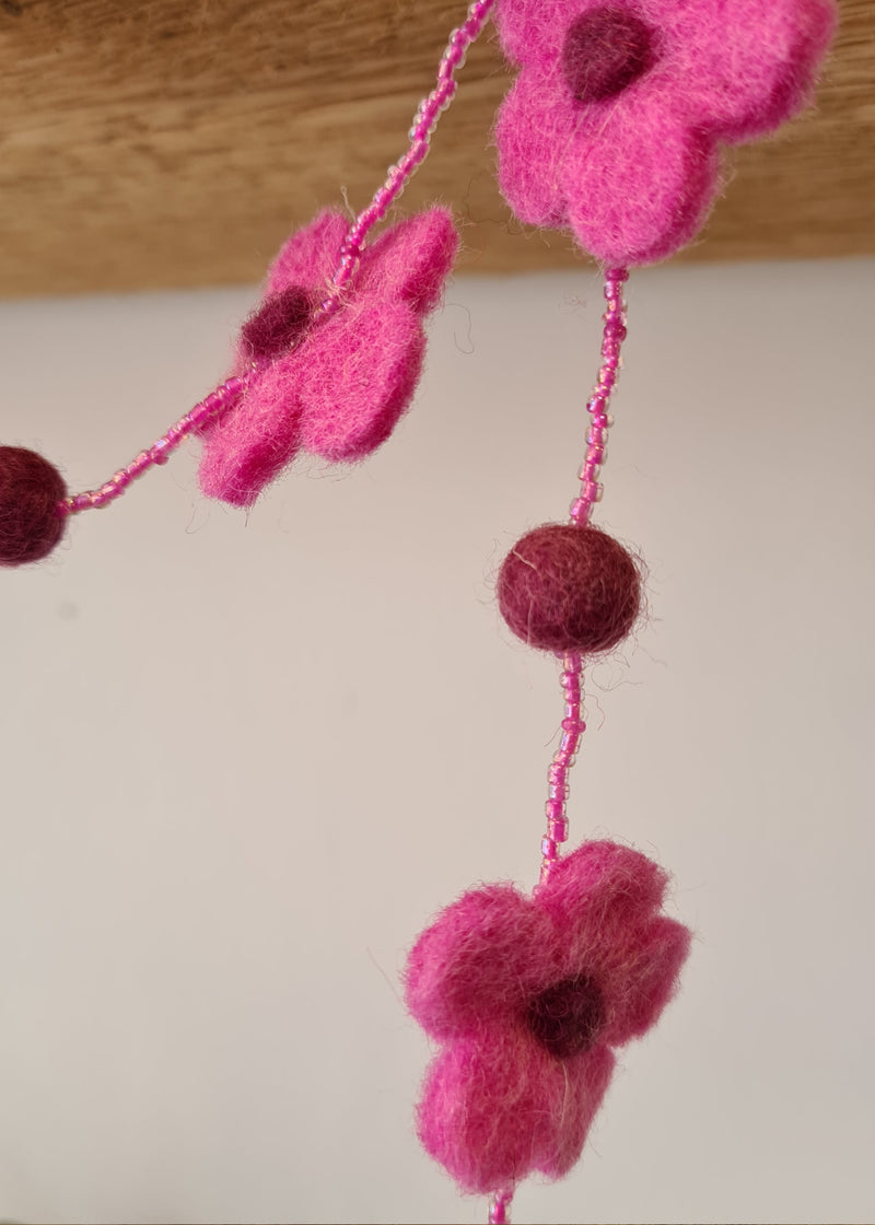 close up of flower and pom pom on a Pink pom pom flower necklace with beads