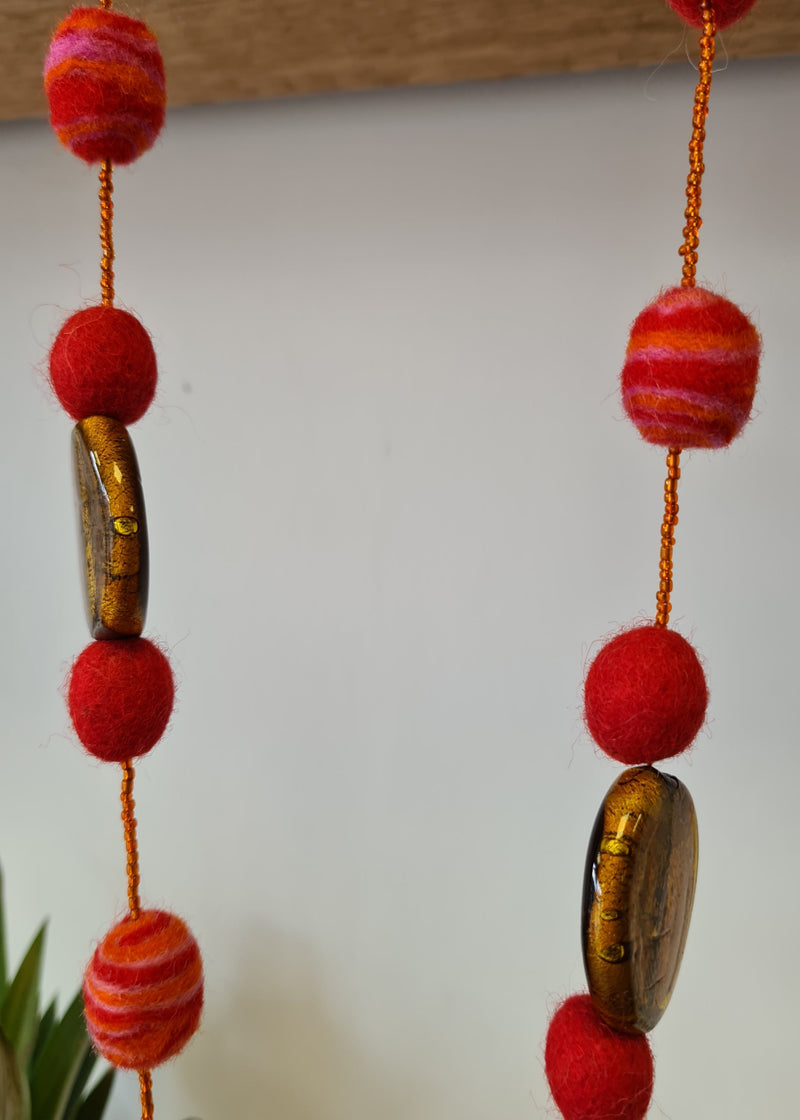 Red Felt Pom Pom Necklace with swirl detail hanging and brown murano style glass pendant